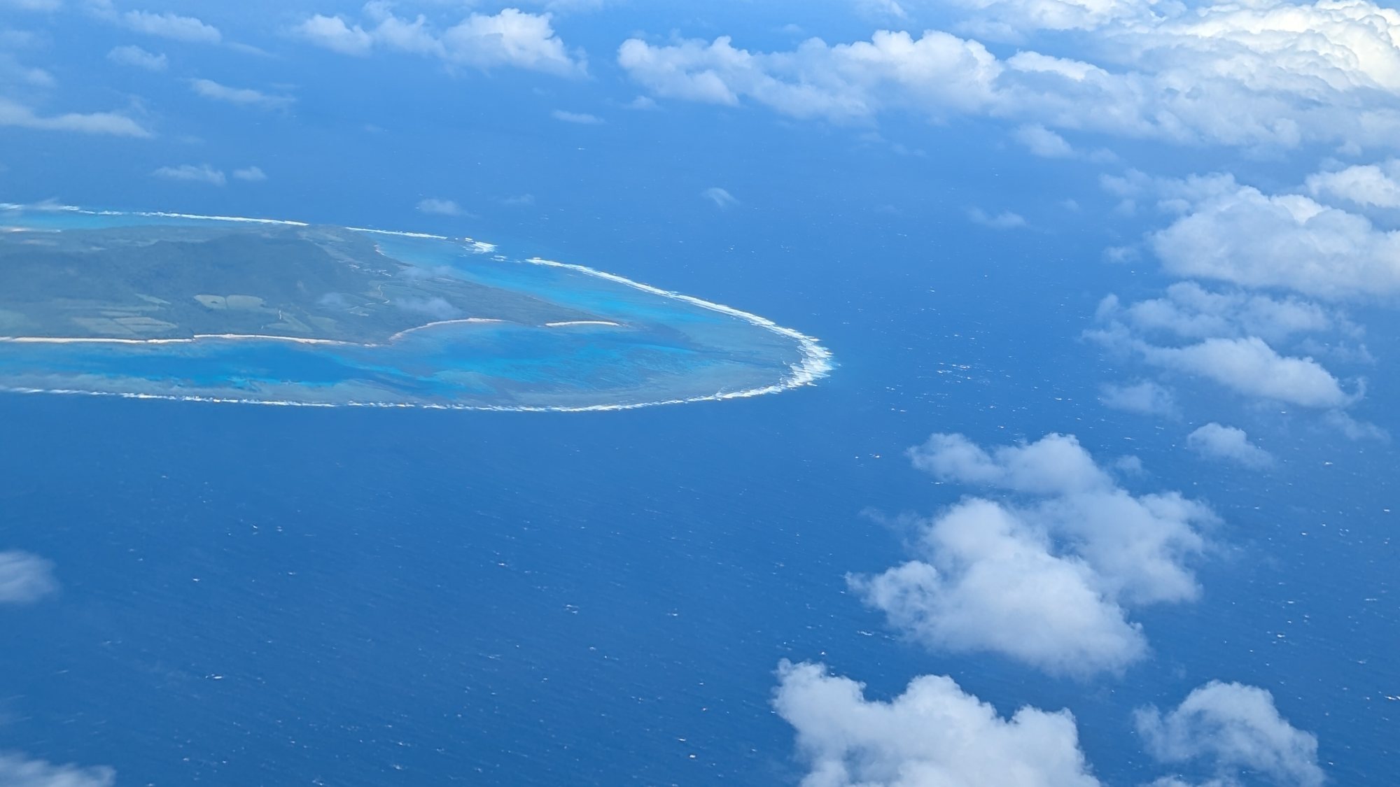 飛行機の窓から眺める青い海と島
